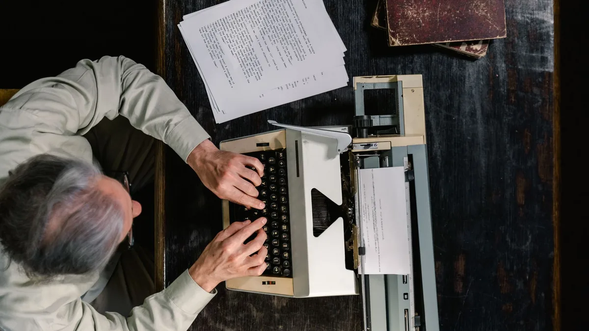 A person typing on a vintage typewriter with scattered p 9572522